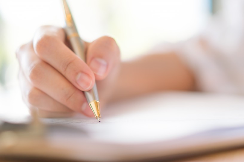 Hand with pen over application form .